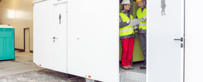 Workers inspecting a restroom trailer before renting it out