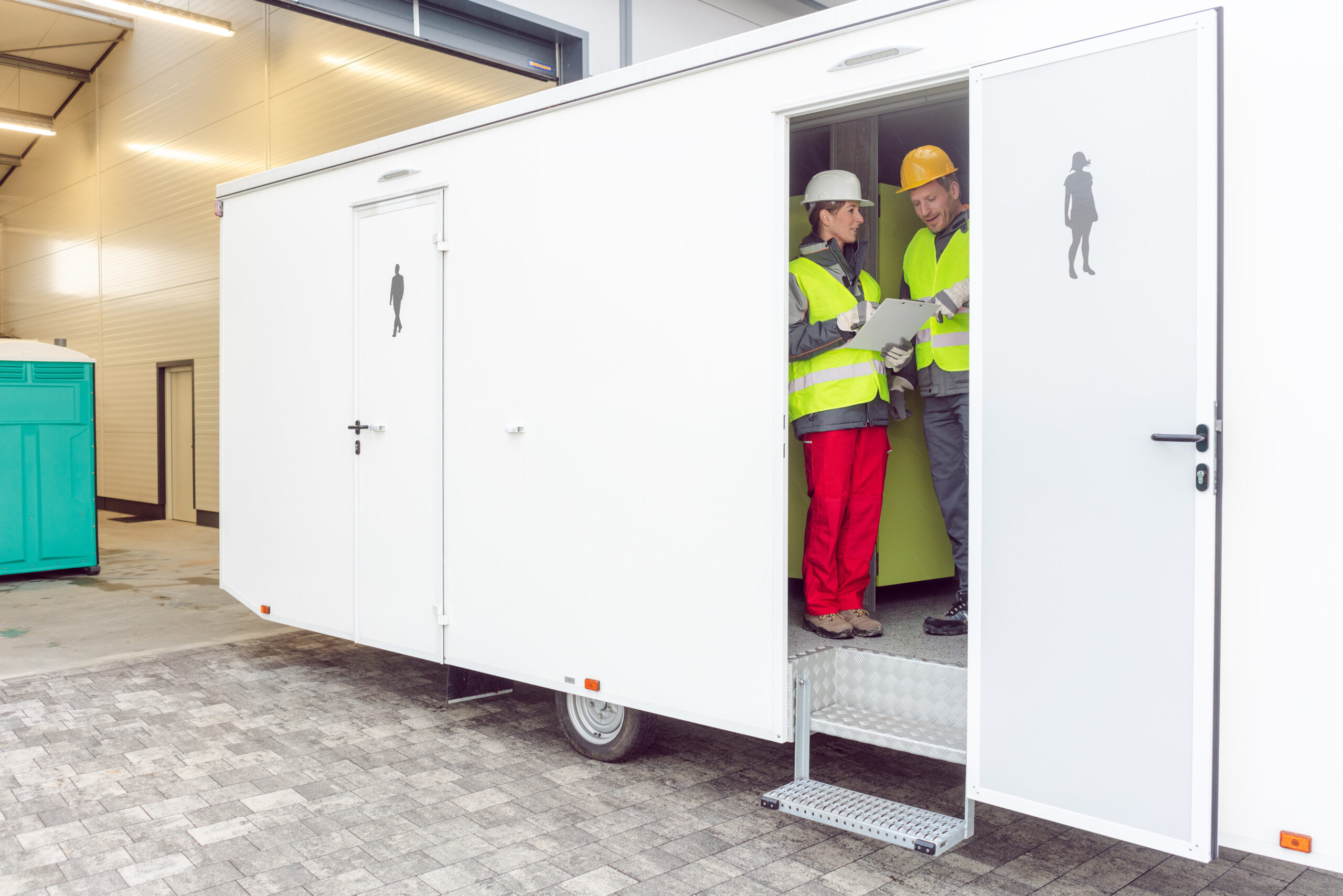 Workers inspecting a restroom trailer before renting it out